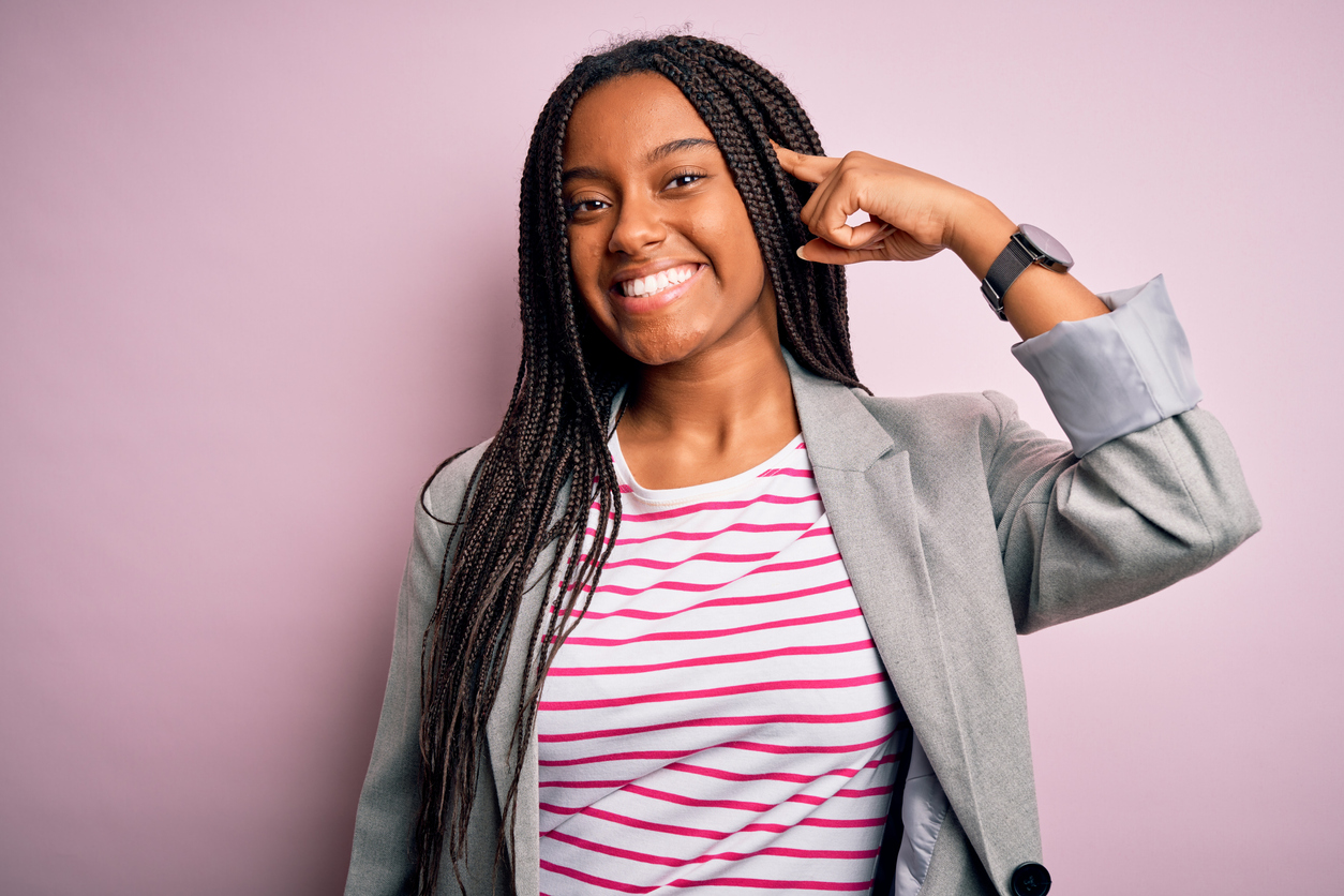 Young african american business woman standing over pink isolated background Smiling pointing to head with one finger, great idea or thought, good memory